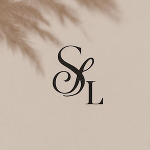 May include: Elegant black monogram logo featuring the letters "S" and "L" in a stylish, flowing script. The design is set against a soft, neutral beige background with subtle shadow details, creating a sophisticated aesthetic.