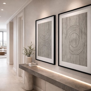 May include: A hallway with two framed abstract art prints. The prints feature black and white geometric designs. A console table with a vase of greenery and books sits below the artwork. The hallway has a neutral color palette.