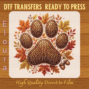 May include: A DTF transfer sheet featuring a central animal paw print design composed of brown and gold rhinestones, surrounded by autumn leaves and acorns. The text reads DTF TRANSFERS READY TO PRESS, Eloura, and High Quality Direct to Film.