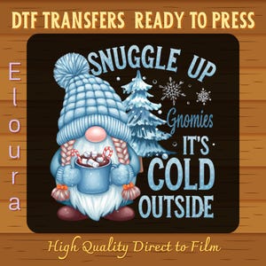 May include: A whimsical design featuring a gnome wearing a blue hat and holding a mug of hot cocoa with marshmallows and candy canes. The text reads "Snuggle Up Gnomies, It's Cold Outside." The image is labeled "DTF Transfers Ready to Press."
