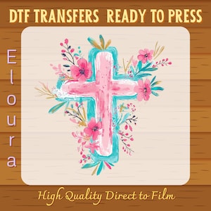 May include: A pink cross design with a turquoise outline and floral accents. The image includes the text "DTF TRANSFERS READY TO PRESS", "Eloura", and "High Quality Direct to Film". The design is on a light beige background.