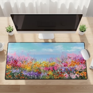 May include: A rectangular mouse mat with a colourful floral design. The image depicts a field of flowers in shades of red, pink, yellow, and purple against a blue sky. Designed to fit under a computer and mouse.