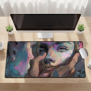 May include: A rectangular desk mat with a colourful artistic illustration of a person looking into a mirror. The artwork uses blues, pinks, and yellows. A computer monitor, mouse, and small plants are also visible.