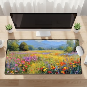 May include: A rectangular desk mat featuring a vibrant landscape painting. The artwork depicts a field of colorful wildflowers in shades of yellow, red, and purple, with a backdrop of rolling hills and a blue sky. The mat is designed to protect the desk surface.