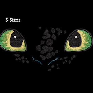 May include: Embroidered design of a dragon's face, featuring two large, almond-shaped eyes with green and yellow details. The design includes the text "5 Sizes" in white, indicating available size options. The dragon's face is black.