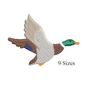 May include: An embroidered patch of a flying duck with outstretched wings. The duck features a green head, brown body, white and tan wings, and an orange beak. The text "9 Sizes" is below the duck.