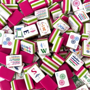 May include: A collection of rectangular mahjong tiles featuring a vibrant color scheme of hot pink, lime green, and white. The tiles display various intricate illustrations, including bamboo stalks, floral patterns, and directional letters.