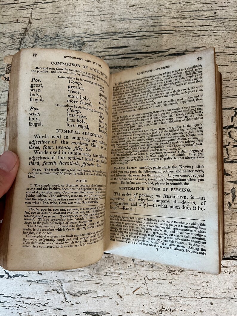 May include: A page from an old book about the English language, focusing on the comparison of adjectives. The text discusses the positive, comparative, and superlative forms of adjectives, as well as the use of numerical adjectives.