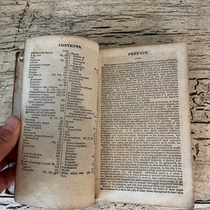 May include: An open book with a yellowed, aged appearance. The pages contain a table of contents with headings such as "Nouns", "Gender of", "Person of", "Number of", "Case of", "Orthography", "Parsing", "Participles", "Prepositions", "Pronouns", "Personal", "Compound Personal", "Relative", "Pronounciation", "Prosody", "Provincialisms", "Punctuation", "Rhetorick", "Rules of Syntax", "Sentences", "Terminations", "Transposition", "Standard of Grammatical Syntax", "To", "Tenses", "Signs of the", "The", "That", "Verbs", "Active-Transitive", "Active-Intransitive", "Passive", "Neuter", "Defective", "Auxiliary", "Irregular", "Compound", "Regular", "Versification", "Worth", "What, which, who", "You".