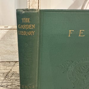 May include: A vintage green book from "The Garden Library" series, featuring gold lettering and embossed botanical illustrations. The book's spine reads "Ferns."