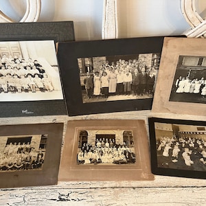 May include: Six black and white framed photographs of school children standing in front of a building. The photos are arranged in two rows of three. The photos are all in vintage style frames.