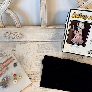 May include: A vintage string art kit with a box featuring a pink and white angel design. The kit includes instructions, thread, nails, and a black fabric piece. The box text reads "String Art Kit" and "Easy Completion".