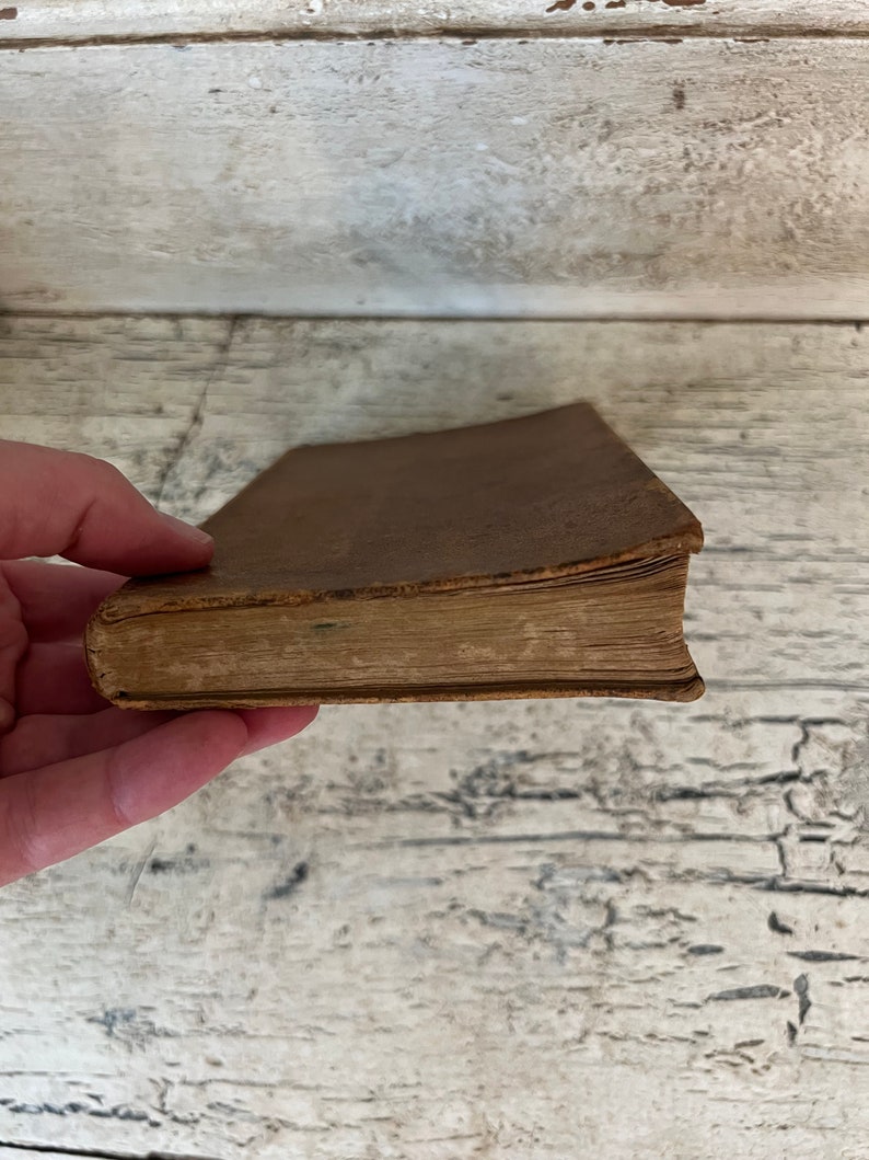 May include: A brown leather-bound book with aged pages. The book is closed and the spine is visible.