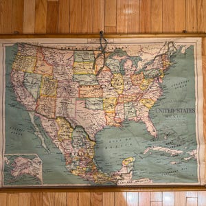 May include: A vintage pull-down wall map of the United States and Mexico featuring muted pastel colors for state boundaries, a light green ocean background, and wooden dowels at the top and bottom with a hanging cord attached to the top rod.