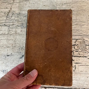 May include: A brown leather-bound book with a worn cover.