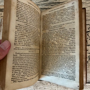 May include: An open book with yellowed pages and a brown leather cover. The book is open to a page with text about grammar and the use of relative pronouns. The text is in a small font and is difficult to read.