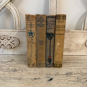May include: A collection of four vintage hardcover books with worn, tan and grey fabric spines. The titles include 'Came to Harbor Light', 'Six Little Bunkers at Grandpa Ford's', 'Dumps: A Plain Girl', and 'Self-Raised', all featuring aged text.