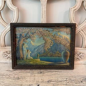 May include: A rectangular framed print featuring a landscape scene with two figures standing under a large flowering tree. The background displays blue mountains, a calm lake, and two vases placed on a ledge. The frame is dark brown with a textured finish.