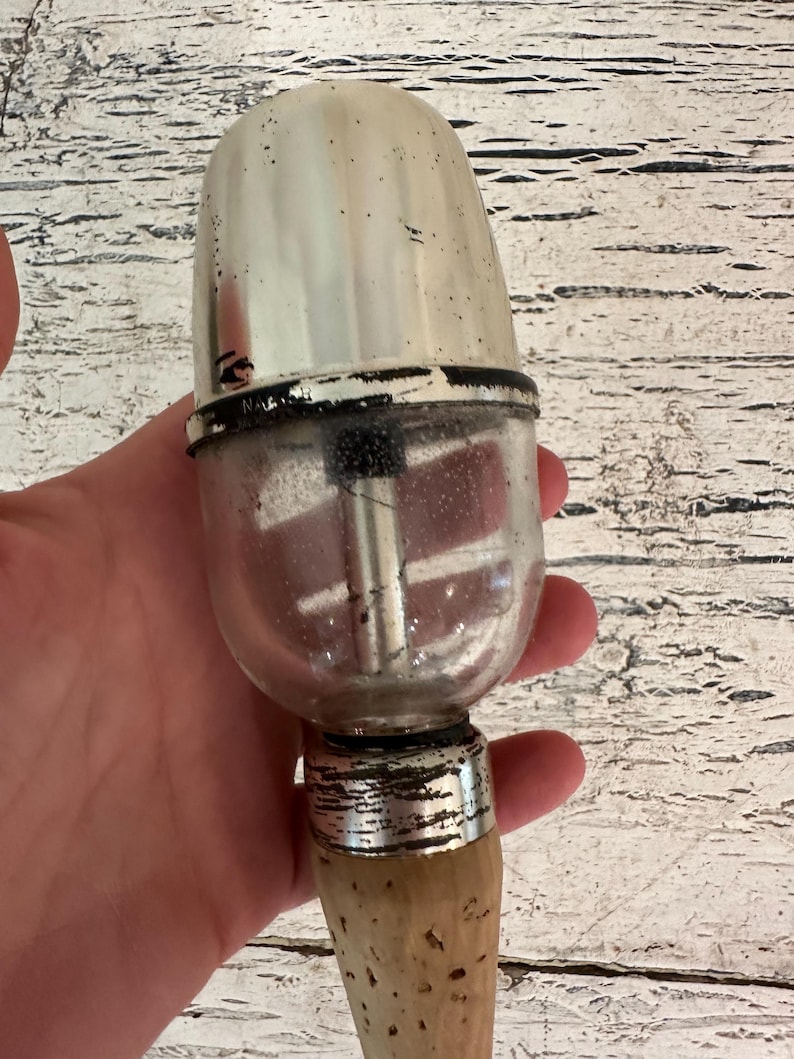 May include: A vintage silver and glass bottle stopper with a wooden handle. The stopper has a clear glass bulb with a metal insert and a silver top.