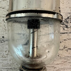 May include: A silver and glass vintage soda dispenser with a black rubber ring and a black metal rod inside the glass chamber.