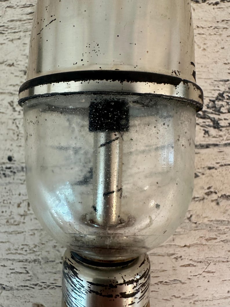 May include: A silver and glass vintage soda dispenser with a black rubber ring and a black metal rod inside the glass chamber.