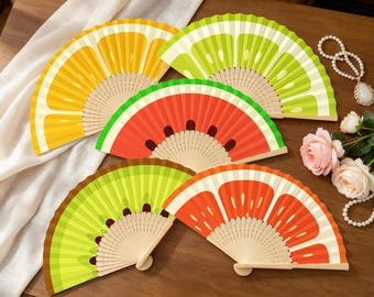Ventagli pieghevoli con motivo frutta, ideali come bomboniere per feste estive hawaiane o come accessorio per feste in spiaggia tropicali.