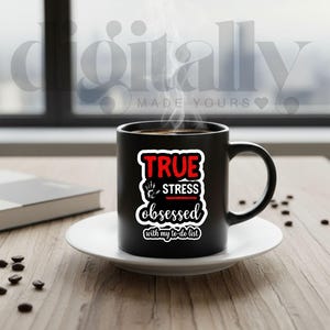 May include: A black ceramic mug with the text "TRUE STRESS obsessed with my to-do list" in red and white. The mug sits on a white saucer, with coffee beans scattered around. Steam rises from the coffee, suggesting it's hot.