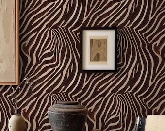 May include: A room interior featuring wallpaper with a dark brown and cream zebra stripe pattern. A wooden console table holds a dark ceramic vessel, stacked books, and a small sculpture. A black-framed artwork hangs on the patterned wall.
