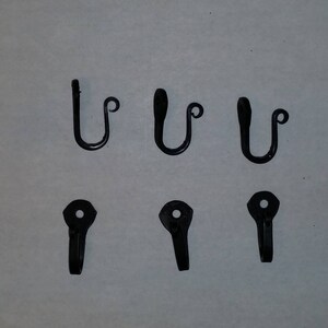 May include: Six black metal hooks, three with a simple design and three with a curved hook. These hooks are great for hanging items on a wall.