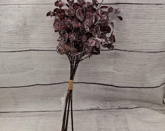 May include: A bouquet of artificial eucalyptus stems with burgundy leaves. The stems are bundled together with twine.