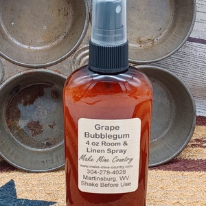 May include: A 4 ounce bottle of Grape Bubblegum Room & Linen Spray. The bottle is brown glass with a black spray top. The label is white with black text and says "Grape Bubblegum 4 oz Room & Linen Spray Make Mine Country www.make-mine-country.com 304-279-4028 Martinsburg, WV Shake Before Use"