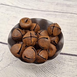 May include: A bowl filled with rusty brown metal jingle bells. The bells are round and have a cross-shaped design on the top.
