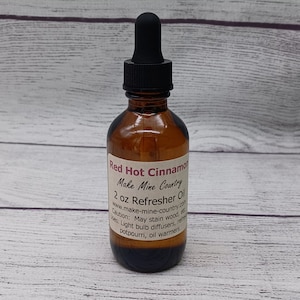 May include: A 2 ounce bottle of Red Hot Cinnamon Refresher Oil from Make Mine Country. The bottle is amber glass with a black dropper top. The label is white with black text. The text on the label reads "Red Hot Cinnamon", "Make Mine Country", "2 oz Refresher Oil", "www.make-mine-country.com", "Caution: May stain wood, etc.", "Uses: Light bulb diffusers, refreshers, potpourri, oil warmers".