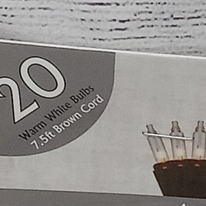 May include: A package for 20 warm white LED Christmas lights with a 7.5 ft brown cord. The package shows a close-up of the lights.