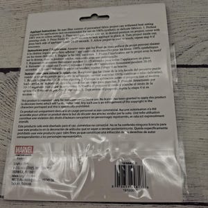 May include: A clear plastic packet containing a Marvel iron-on applique. The packet has instructions in English, French, and Spanish. The Marvel logo is visible, along with the Simplicity brand.