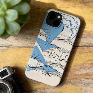 May include: A white phone case with a blue bird design and musical notes. The case has the text "In sixths" and "ary motion". The case is on a wooden surface.