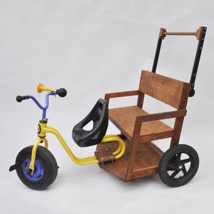 以下が含まれることがあります： 木製の座席と押し棒が付いた、黄色と青色の三輪車。 三輪車には黒い座席、黒い車輪、黄色のホーンが付いています。 木製の座席と背もたれは、明るい茶色の木材で作られています。