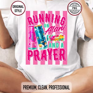 May include: White t-shirt with a pink and white striped design. The shirt features the text "RUNNING ON Alani AND A PRAYER" in pink and green. Three Alani energy drink cans are also displayed.