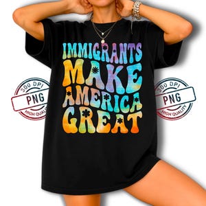 Pode incluir: Camiseta preta com a frase "IMMIGRANTS MAKE AMERICA GREAT" em uma fonte colorida em estilo tie-dye. O design apresenta uma estética retrô com uma mensagem ousada e chamativa. A camiseta é um estilo casual e confortável.