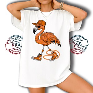 May include: White t-shirt with a cartoon flamingo design. The flamingo is orange, wearing sunglasses, a hat, and trainers. It has a beaded necklace. The design is a fun, whimsical illustration.