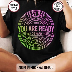 Puede incluir: Camiseta negra con un diseño circular que dice "TEST DAY" en un degradado verde y morado. El diseño incluye el texto "YOU ARE READY" y "DO YOUR BEST". La camiseta también tiene el texto "ZOOM IN FOR REAL DETAIL".