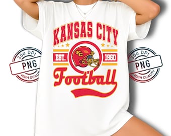 Könnte beinhalten: Weißes T-Shirt mit einem rot-goldenen Aufdruck. Das Design enthält die Wörter "KANSAS CITY Football" und einen Football-Helm mit dem Text "EST. 1960". Das T-Shirt hat kurze Ärmel.