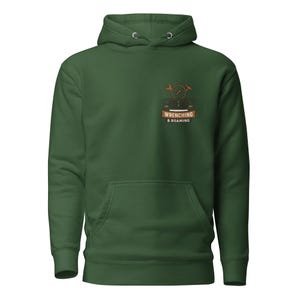 May include: A forest green hooded sweatshirt featuring a front kangaroo pocket and a small graphic on the left chest. The graphic depicts a vehicle front, a compass, a wrench, and a hammer with the text WRENCHING & ROAMING on a banner.