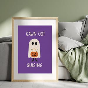 May include: A framed Halloween print with a purple background. The print features a cartoon ghost holding a jack-o'-lantern and the words "GAWN OOT GUISING" in white. The frame is a light wood colour.