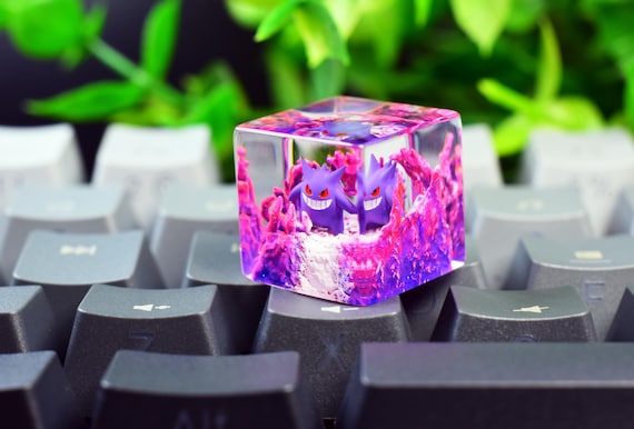 A hand-cast resin artisan keycap featuring a Gengar sculpt inside a translucent cube — the kind of tiny desk art that makes mechanical keyboard enthusiasts immediately stop scrolling.