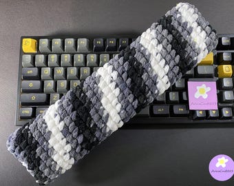 May include: A gray, white, and black striped keyboard wrist rest is placed on a mechanical keyboard. The wrist rest is made of a soft, textured material. A sticker with the text "AriesCraft263" is visible.