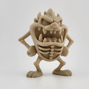 May include: A tan 3D-printed figurine of the Tasmanian Devil cartoon character. The figurine has an open mouth with visible teeth, arms at its sides, and a ribcage design. The figurine is standing on a white surface.