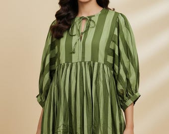 May include: A midi-length dress featuring vertical stripes in alternating shades of olive and sage green. The garment has three-quarter length puff sleeves, a round neckline with a central slit, and a tie closure at the collar with gathered fabric.