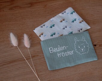 Puede incluir: Dos toallitas para bebés, una azul claro con un estampado de coches y otra turquesa con el texto "Beulentröster" y una cara de llama. Dos flores secas esponjosas de color rosa claro también están en la imagen.