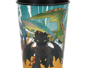 May include: A cylindrical cup featuring a black dragon with green eyes and other colorful dragons. The cup has a black rim and a yellow and teal background with white accents. The design is a cartoon style.